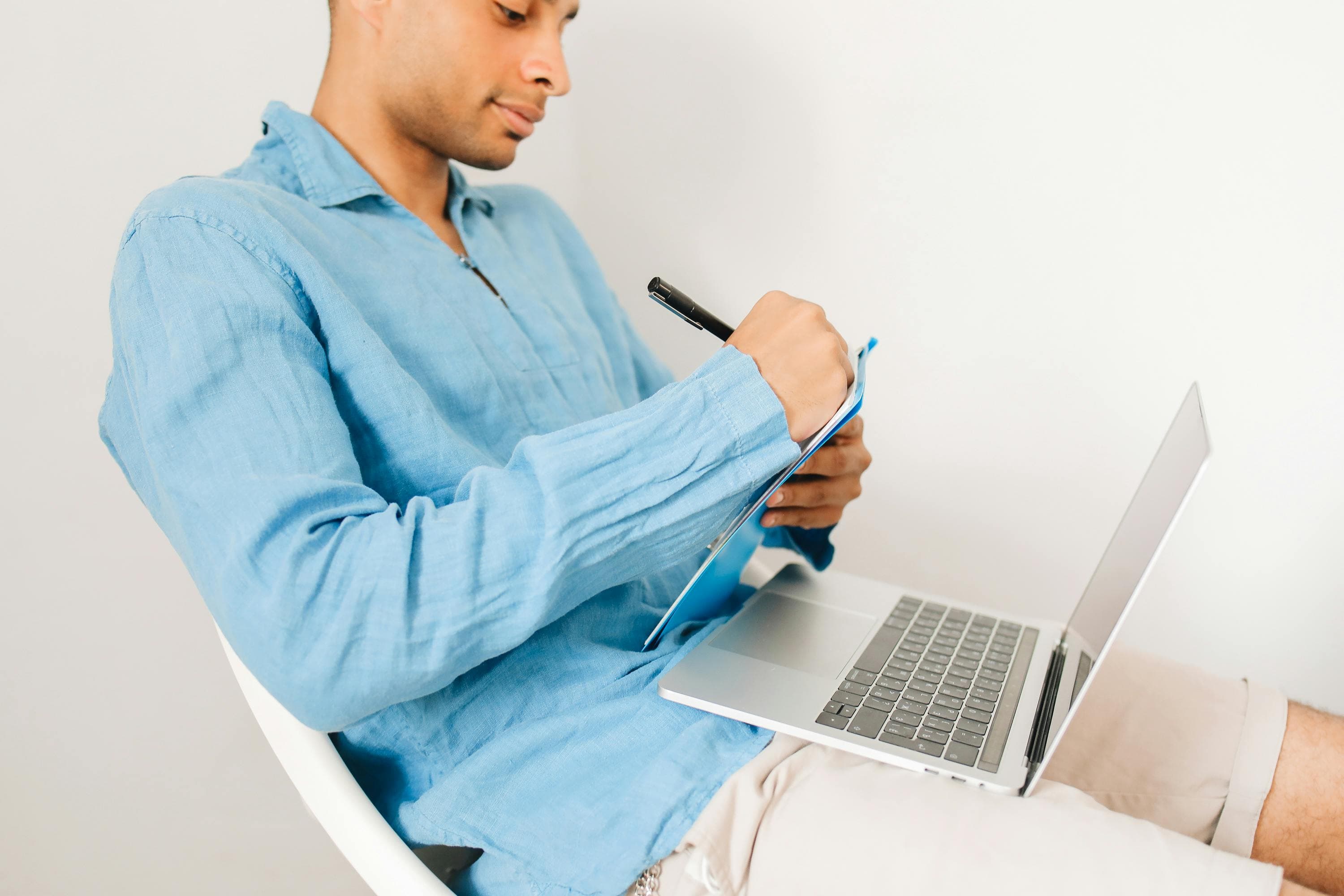 Man filling out form with open laptop.